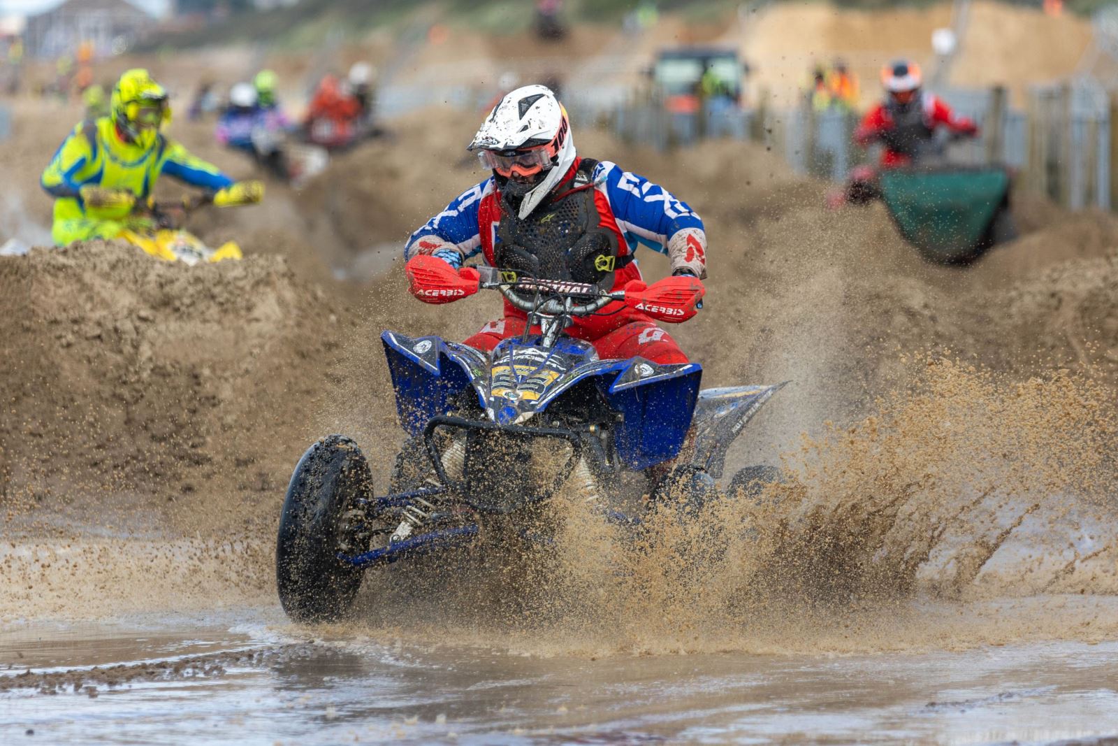 A quad bike and rider splash through a puddle at the Weston-super-Mare Beach Race